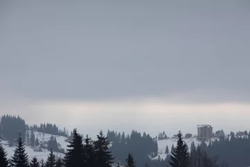 Fotobehang Mistig bos landschapsmening van besneeuwde winterbergen