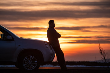 Naklejka na ściany i meble man standing near car on sunset. car travel concept