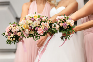 Obraz na płótnie Canvas Bride and bridesmaids in pink dresses posing with bouquets at wedding day. Happy marriage and wedding party concept