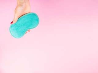 Female hands with red manicure holding turquoise sleeping mask over trendy pink background. Sleep routine, sleep optimization concept.