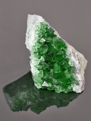 green emerald in geode on dark background