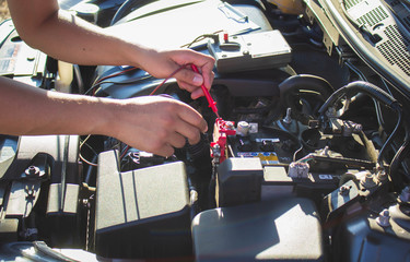 The mechanic is using a voltmeter. Car battery measurement To check readiness for long-distance travel,Concept of car maintenance.