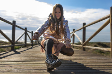 teen tying her shoelaces on wooden walkway