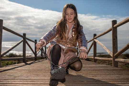 teen tying her shoelaces on wooden walkway