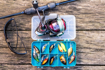 fishing rod and reel with fishing line on a wooden background, sunglasses