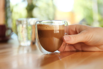 Woman with aromatic coffee at table in cafe, closeup