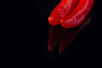 Red chili peppers on black background. Organic ingredient for cooking. Space for text.