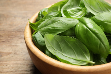 Fresh basil leaves on wooden table, closeup