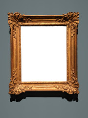 Blank canvas inside an elaborate golden wooden frame on a gray wall. Shadow on top of white canvas...