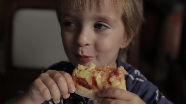 Close up of little cute boy eating pizza. Neutral colors for collor correction.