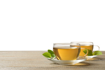 Cups of green tea and leaves on wooden table