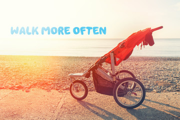 Baby stroller on the background of the sea and deserted beach on a Sunny day. Inscription "walk more often". Nobody
