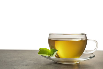 Cup of green tea and leaves on grey table