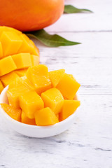 Fresh mango,beautiful chopped fruit with green leaves on bright wooden table background. Tropical...