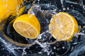 halves of a whole lemon with drops and splashes of water on a black background