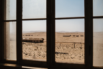 view outside and old desert builing on to other abandoned houses in the sand
