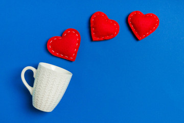Top view of red textile hearts splashing out of a cup on colorful background. Happy Valentine's day concept