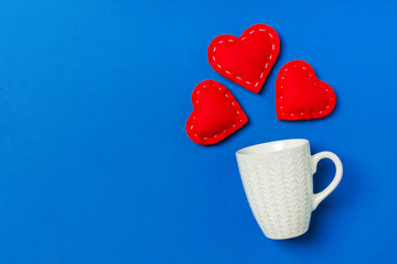 Top view composition of red hearts falling out from a cup on colorful background with copy space. Romantic relationship concept. St Valentaine's Day
