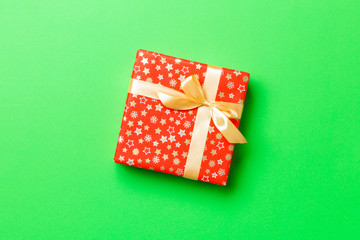 Gift box with gold bow for Christmas or New Year day on green background, top view with copy space