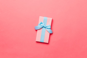 wrapped Christmas or other holiday handmade present in paper with blue ribbon on living coral...
