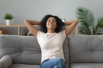 Fototapeta premium Serene african woman leaned on couch resting at home