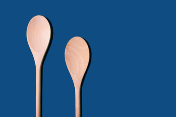 empty wooden spoons on classic blue background top view. copy space. 