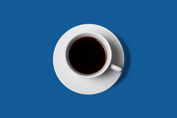 white cup of coffee on classic blue background top view