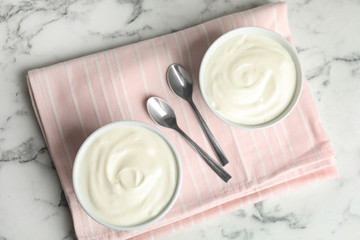 Tasty organic yogurt on white marble table, top view