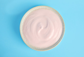Tasty organic yogurt on light blue background, top view