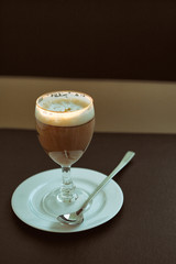 Glass of Irish coffee alcohol drink on brown table.
