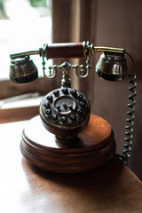 Closeup of wooden and brass antique dial telephone on room table. Colonial decor concept.