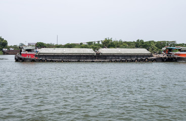 The large cargo boat is floating on the large river.