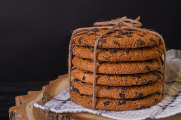 Stack of cookies with chocolate drops. Mouth-watering biscuits on a towel and a piece of wood. Food concept.