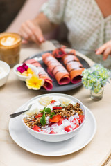 Sweet, vegan and healthy breakfast at Bali cafe. Bowl of homemade granola with yogurt and fresh berries on marble table.