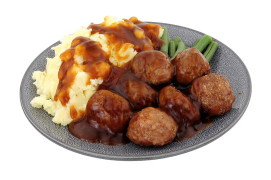 Beef meatballs and mashed potato meal with green beans and gravy isolated on a white background