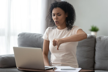 Dissatisfied african woman looking at computer screen showing thumbs down