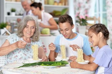 Happy grandmother and grandchildren having breakfast together in kitchen
