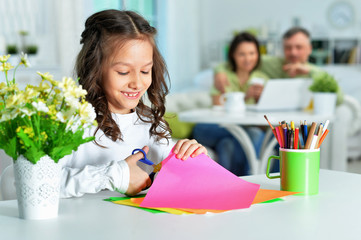 Cute little girl is cutting color paper