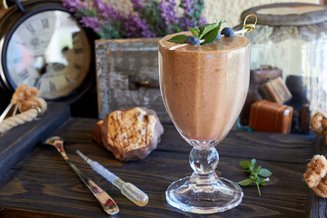 Blueberry smoothie or black currant purple milkshake with mint in the vintage interior of the cafe