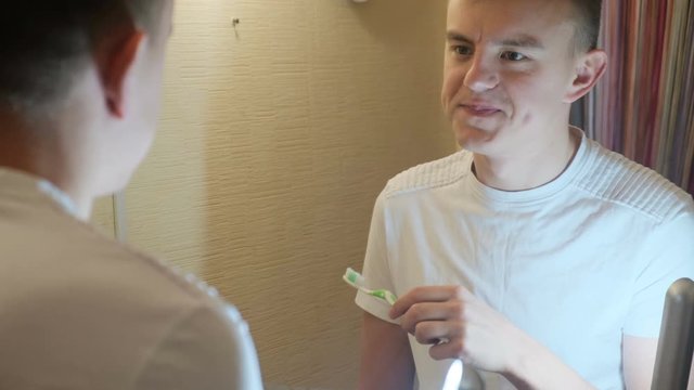 Bad breath. A man looks at his teeth and sniffs a toothbrush after applying