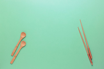 Wooden Cutlery: spoons and Chinese chopsticks on a green background. Zero waste, plastic free.