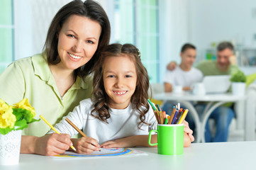 Portrait of little cute girl with mother drawing