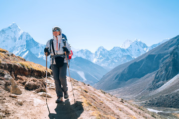 Young hiker backpacker female taking a walking with trekking poles during high altitude Everest Base Camp route near Dingboche,Nepal. Ama Dablam 6812m on background. Active vacations concept