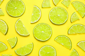 Juicy fresh lime slices on yellow background, flat lay