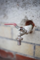 iron water tap protruding from a building wall.