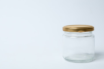 Closed empty glass jar on light background, space for text