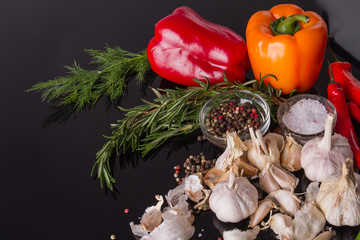 Rosemary and dill. Bell peppers with garkic and condiments. Black surface.