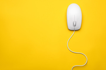 Wired computer mouse on yellow background, top view. Space for text