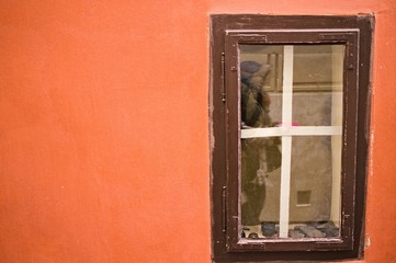 Little wooden window in an orange wall background (Prague, Czech Republic, Europe)