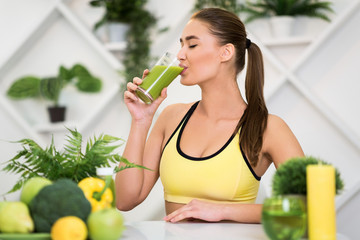Young woman drinking fresh smoothie after home training